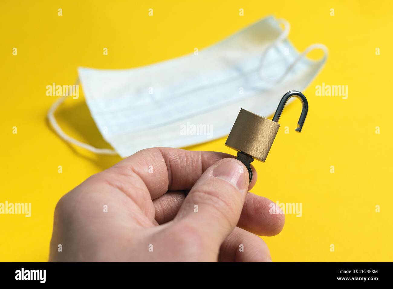 Fine del mondo isolamento della pandemia. Mondo è aperto dopo quarantena coronavirus. Aprire la serratura con chiave in mano sullo sfondo della maschera medica. Foto Stock