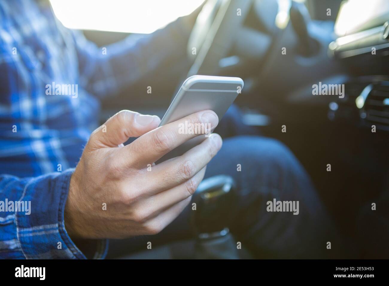 Primo piano di Man in Auto Texting su cellulare Durante la guida Foto Stock