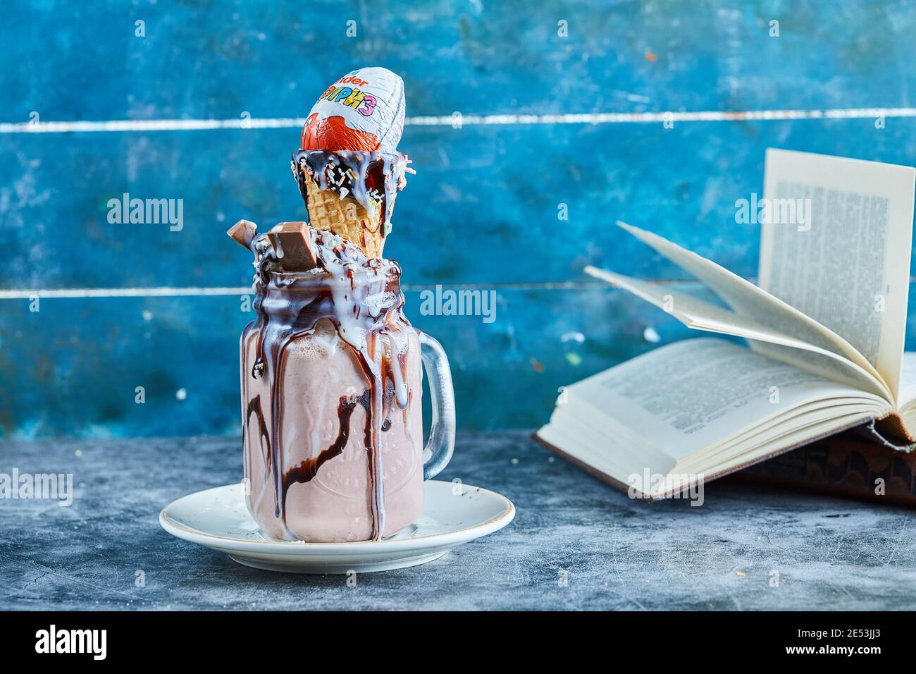 Frullato di cioccolato con barretta di cioccolato, sorpresa di kinder, cono gelato sul piatto bianco Foto Stock