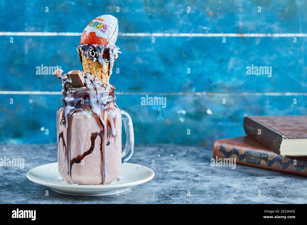 Frullato di cioccolato con barretta di cioccolato, sorpresa di kinder, cono gelato sul piatto bianco Foto Stock