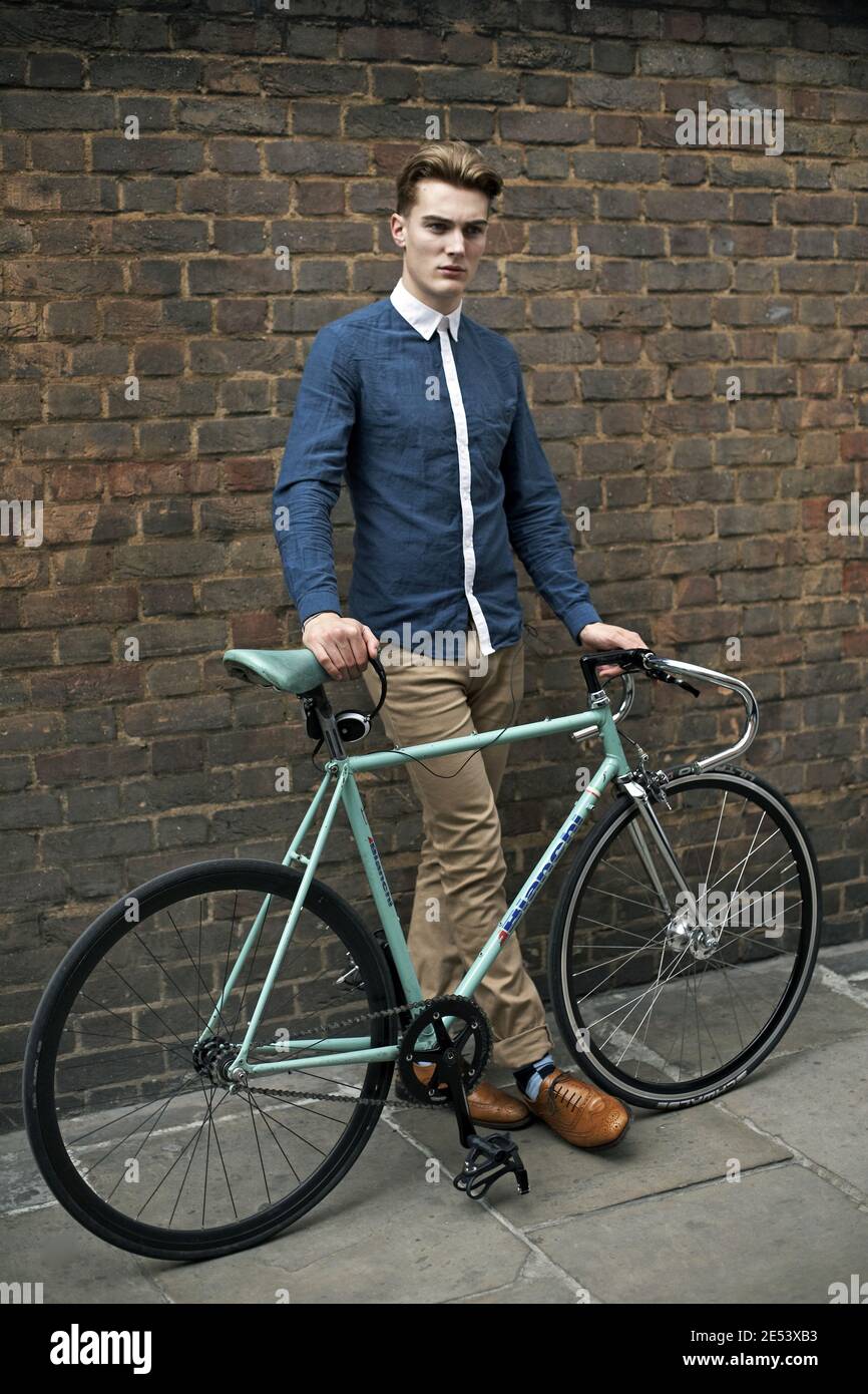 Bell'uomo caucasico in outfit alla moda in posa con una bicicletta d'epoca alla moda sulla strada di Shoreditch , Londra. Foto Stock