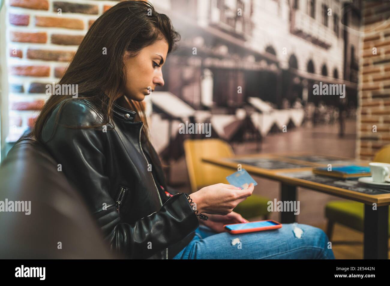 Vista laterale di bella donna che tiene la carta di credito e l'uso smartphone per lo shopping online Foto Stock