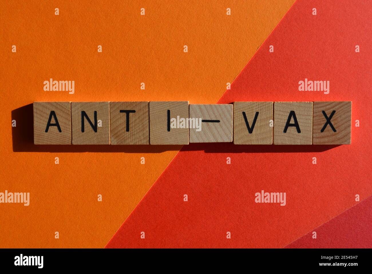 Parola anti-vax in lettere alfabetiche in legno isolate in rosso e. sfondo arancione Foto Stock