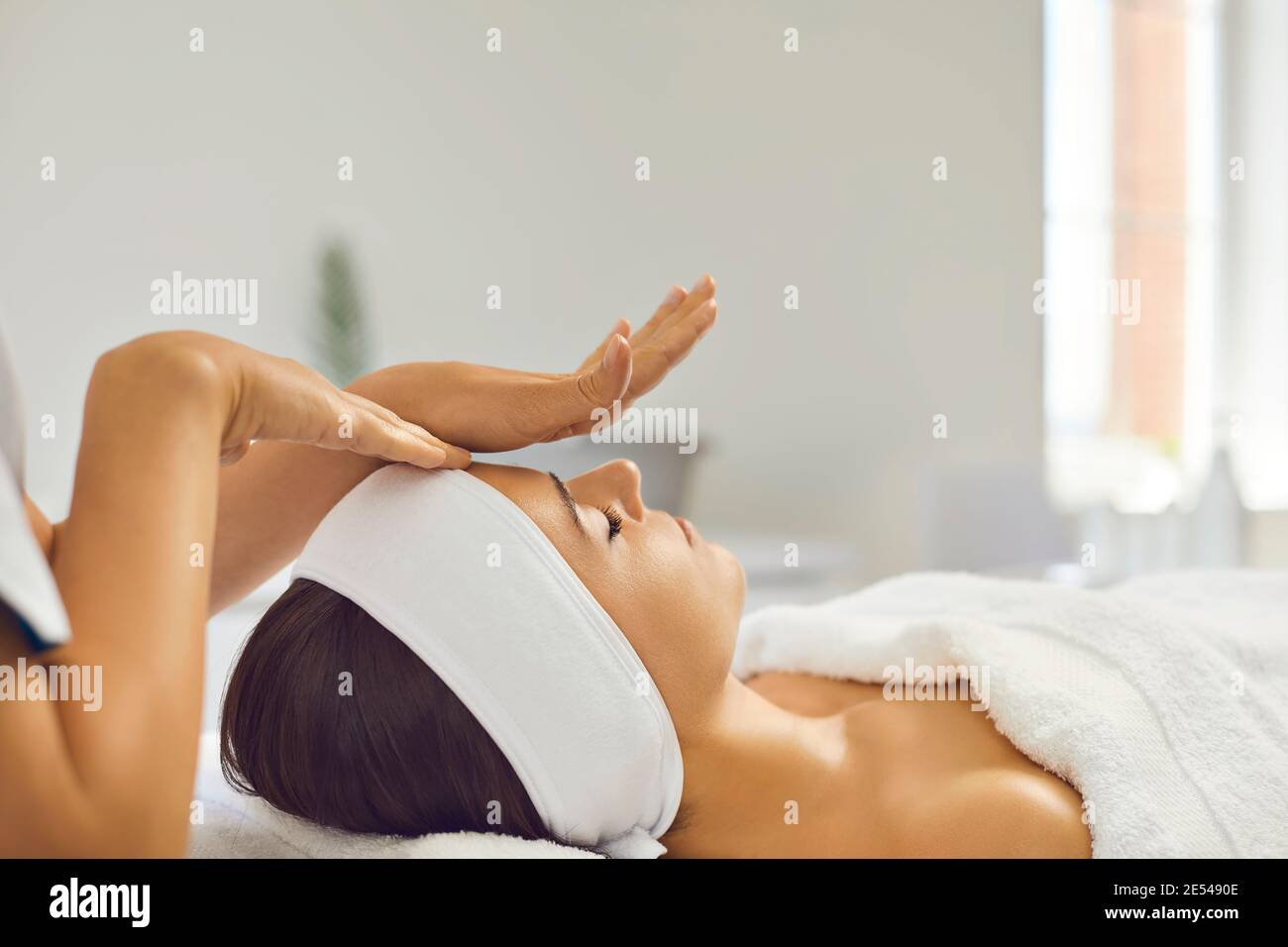 Mani di massaggiatore che fanno un massaggio professionale manuale rilassante del viso per donna Foto Stock