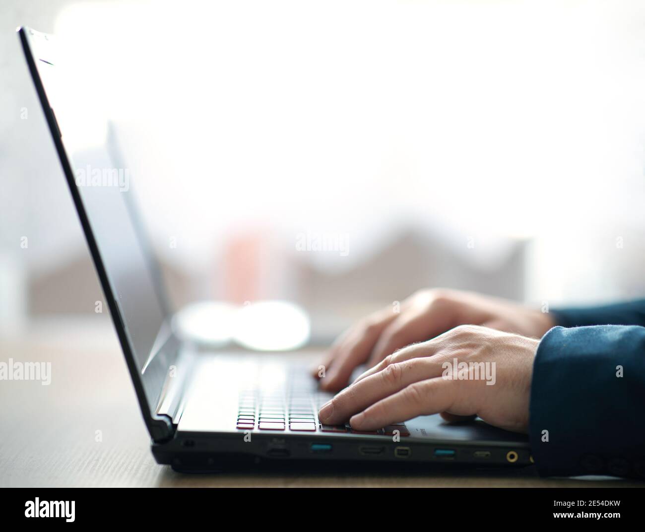 Le mani dell'uomo che digitano sulla tastiera di un computer portatile. Un uomo in ufficio scrive su un computer portatile. Messa a fuoco selettiva Foto Stock