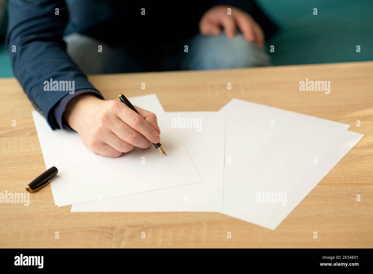 Uomo d'affari in ufficio scrive una lettera o firma una documento su un pezzo di carta bianca con una fontana penna con pennino Foto Stock