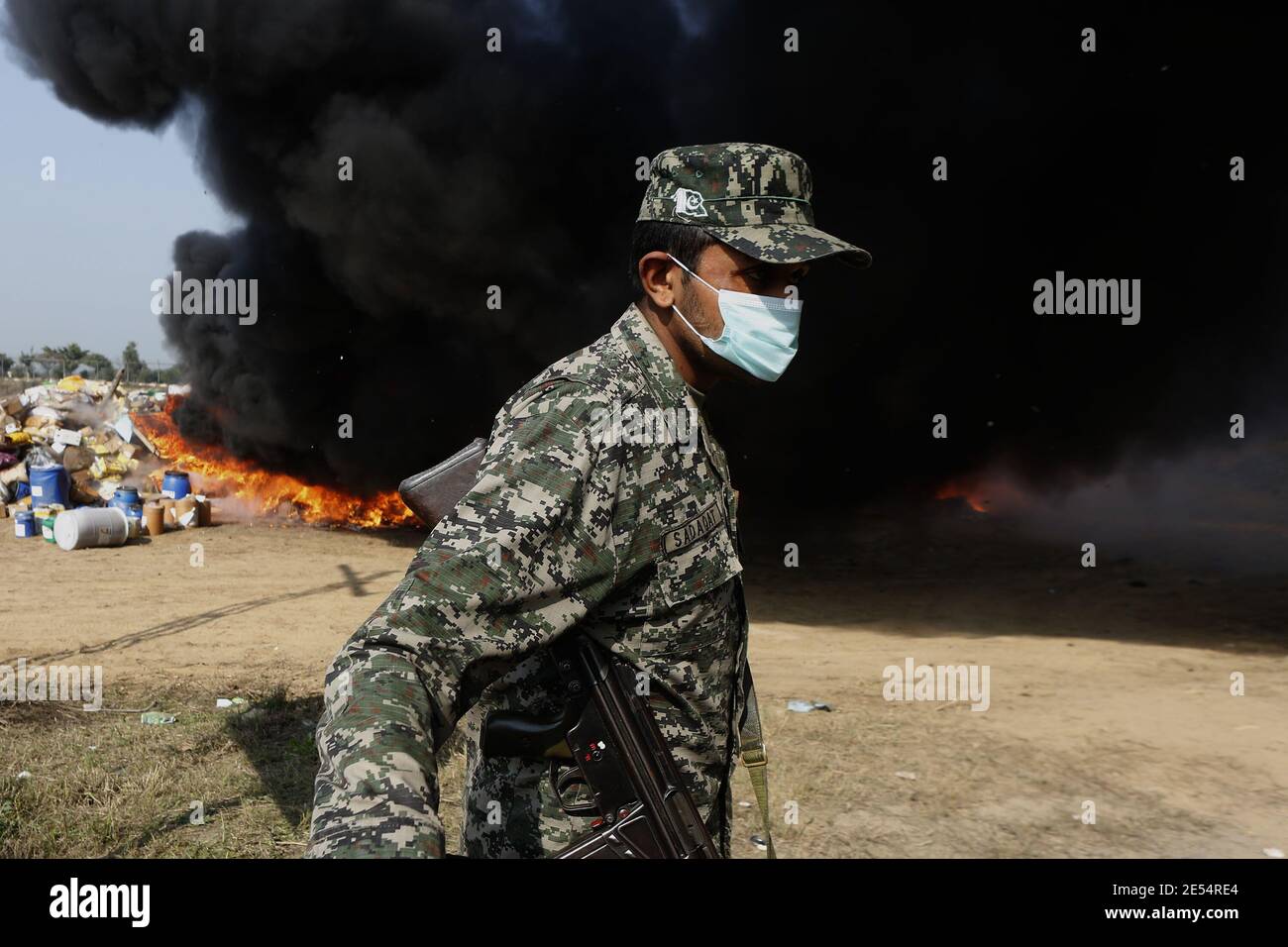 Funzionari doganali che distruggono le bottiglie di alcol e bruciano le droghe sequestrate durante la cerimonia della combustione della droga, alla vigilia della Giornata doganale internazionale Foto Stock