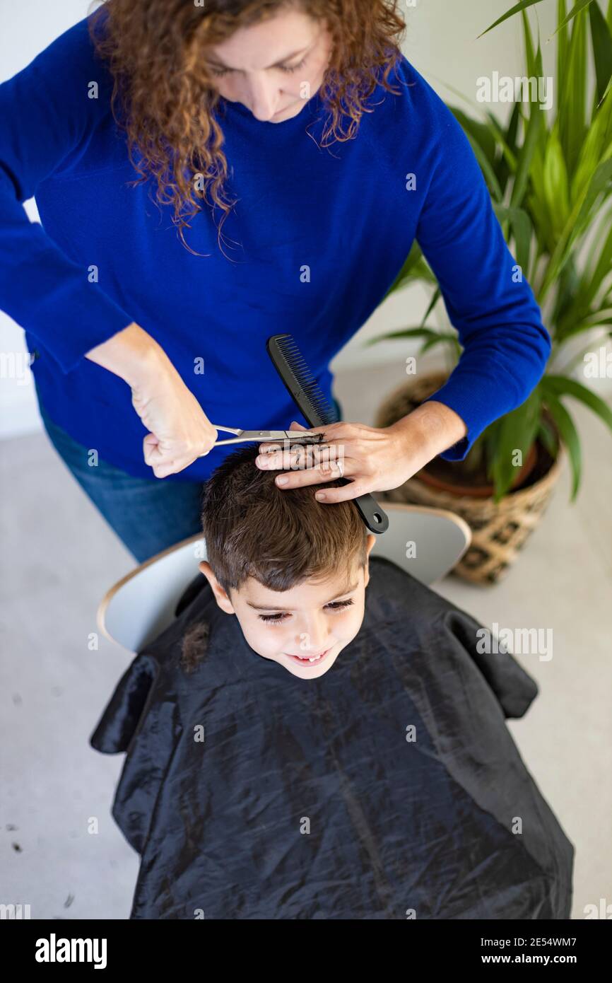 Ragazzo divertente ottenere i capelli tagliati a casa con le forbici Foto Stock