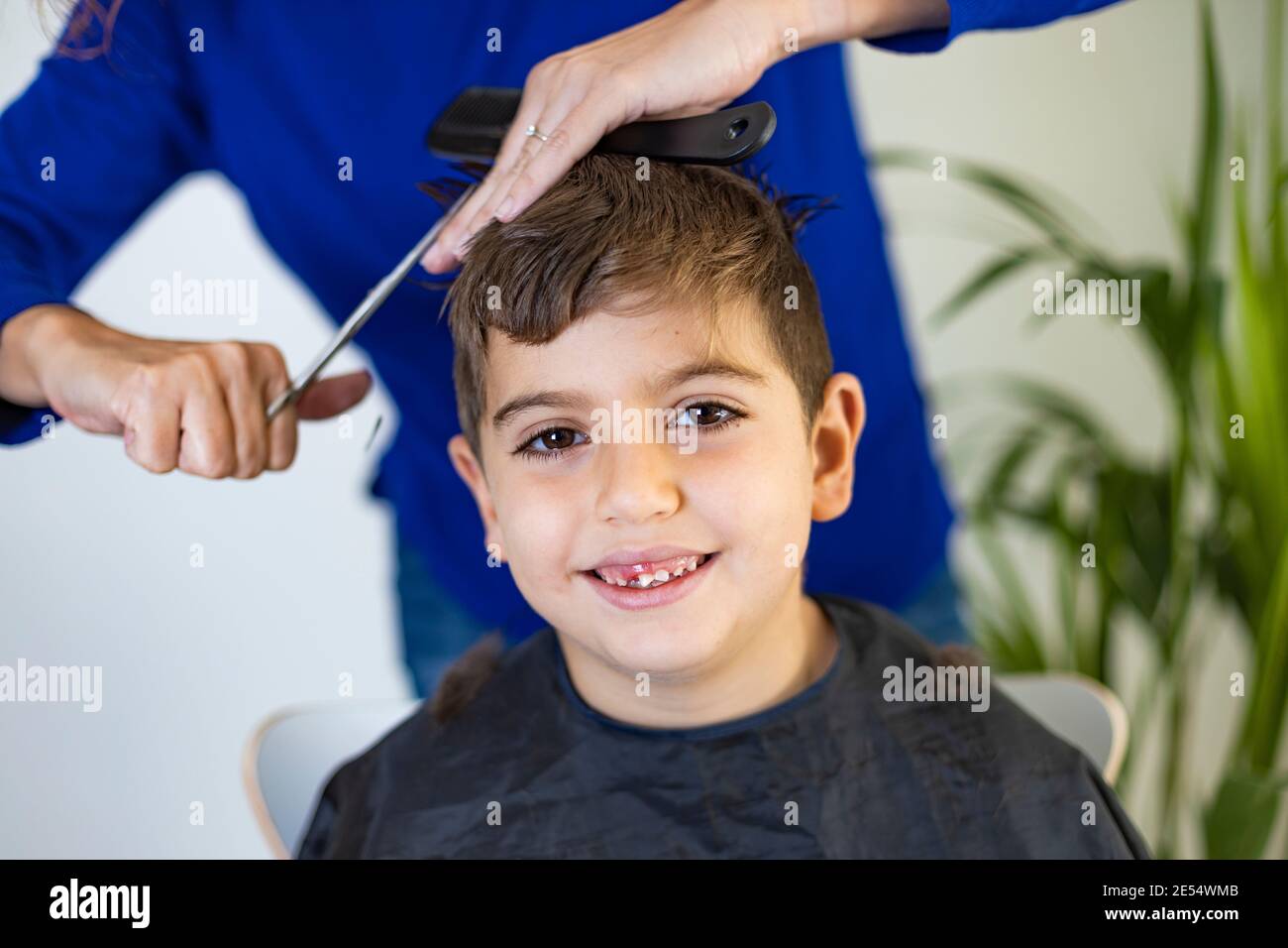 Ragazzo divertente ottenere i capelli tagliati a casa con le forbici Foto Stock