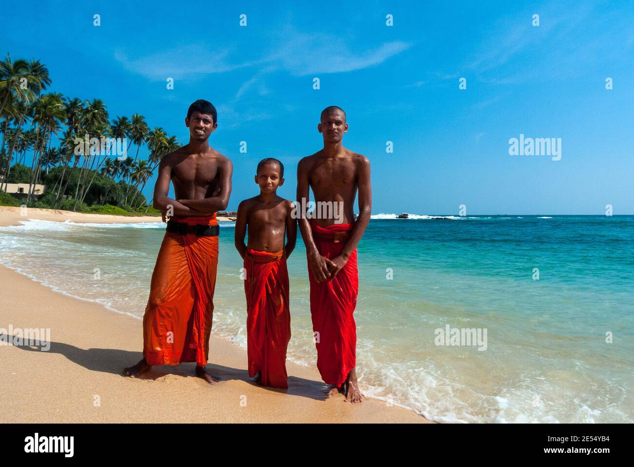 Tangalle, Sri Lanka: Un bambino novizio e due giovani monaci buddisti in riva al mare Foto Stock
