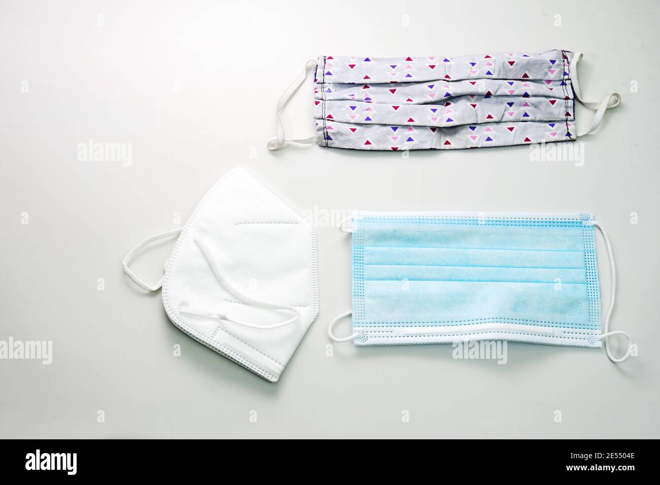 Maschera autoscucita in cotone e due tipi di maschere mediche di protezione, una chirurgica e una maschera ffp2, che sono richiesti in Germania, dorso grigio chiaro Foto Stock
