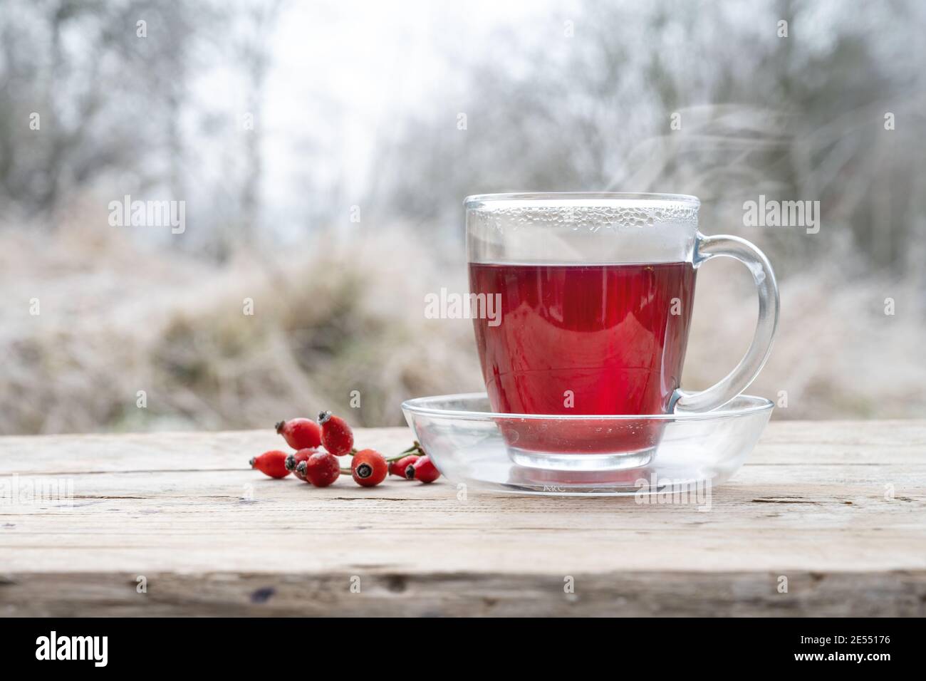 Rosso rosa hip tè e alcuni frutti all'aperto su un rustico tavolo di legno, sano e caldo bevanda calda in una fredda giornata invernale, copia spazio, selezionato fuoco, na Foto Stock