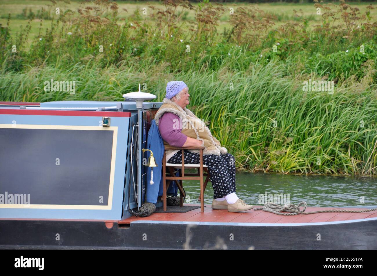Una signora che ama navigare lungo il Tamigi su una chiatta di canale attraverso la campagna vicino Oxford. Oxfordshire, Inghilterra. Foto Stock