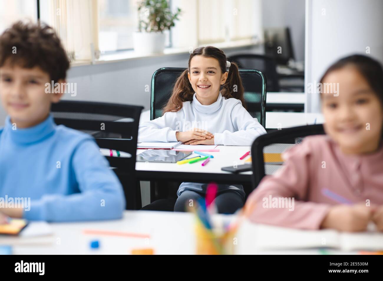 Ritratto di bambina seduta alla scrivania in classe Foto Stock