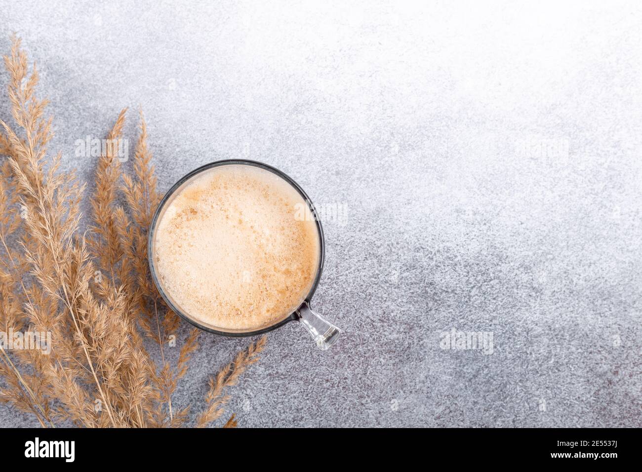 Tavolo con tazza di caffè e fiori secchi su fondo di pietra. Area di lavoro, stile minimalista, disposizione piatta, scrivania home Office con vista dall'alto - immagine Foto Stock