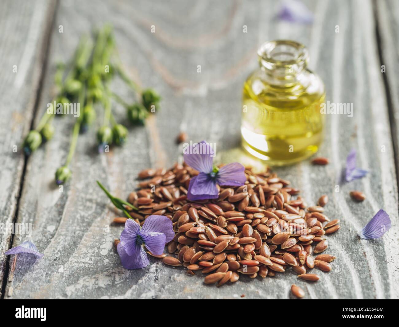 Semi di lino e olio di lino. Semi di lino marrone, olio di lino e fiori di lino blu su vecchio sfondo grigio di legno. Spazio di copia Foto Stock