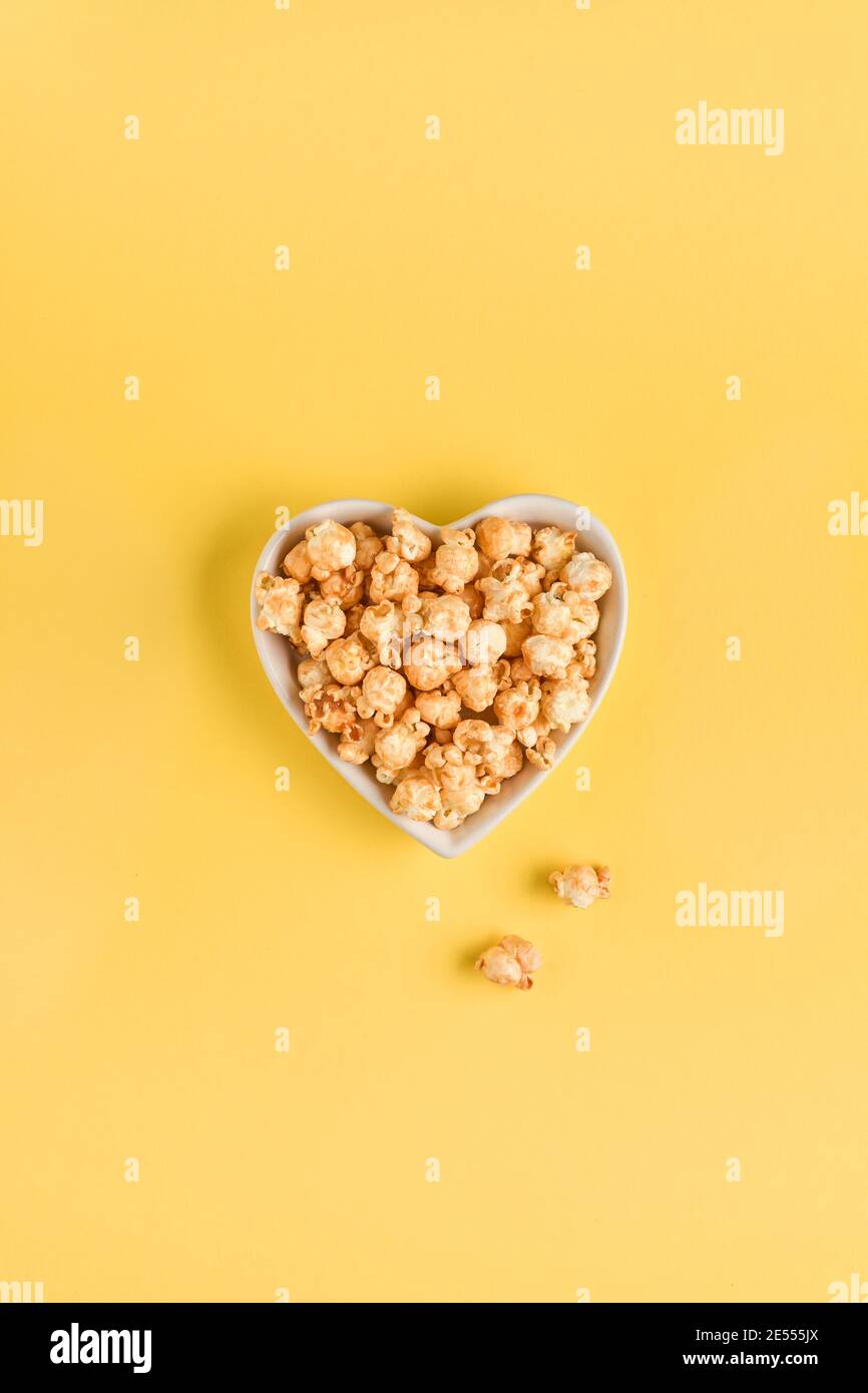 Delizioso popcorn dolce con caramello in ceramica bianca, isolato su fondo giallo tendente. Foto Stock