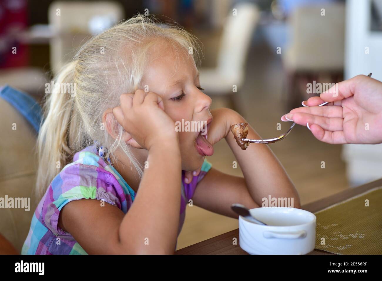 La mano della mamma alimenta la ragazza con un cucchiaio Foto stock - Alamy