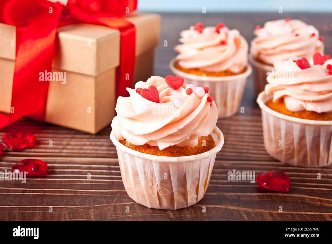 Il formaggio cremoso di San Valentino è stato glassato con caramelle a cuore e scatola regalo sullo sfondo in legno. Concetto di San Valentino. Foto Stock