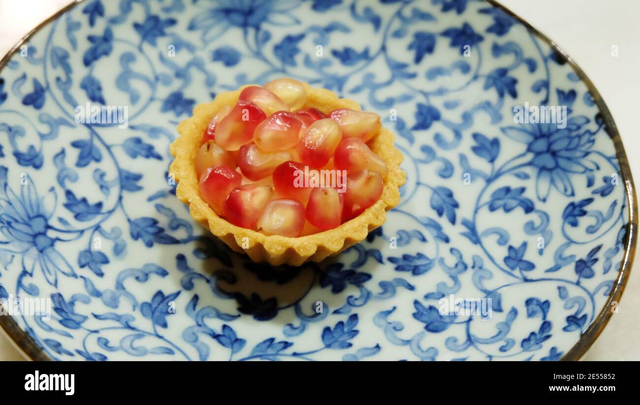 Mini crostata di melograno su un piatto di fiori blu. Foto Stock