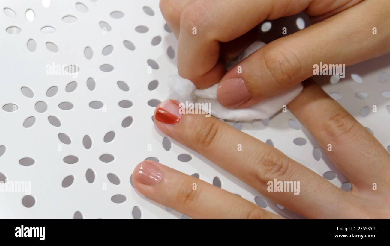 Strofinare a mano lo smalto rosso per unghie con cotone bianco. Foto Stock