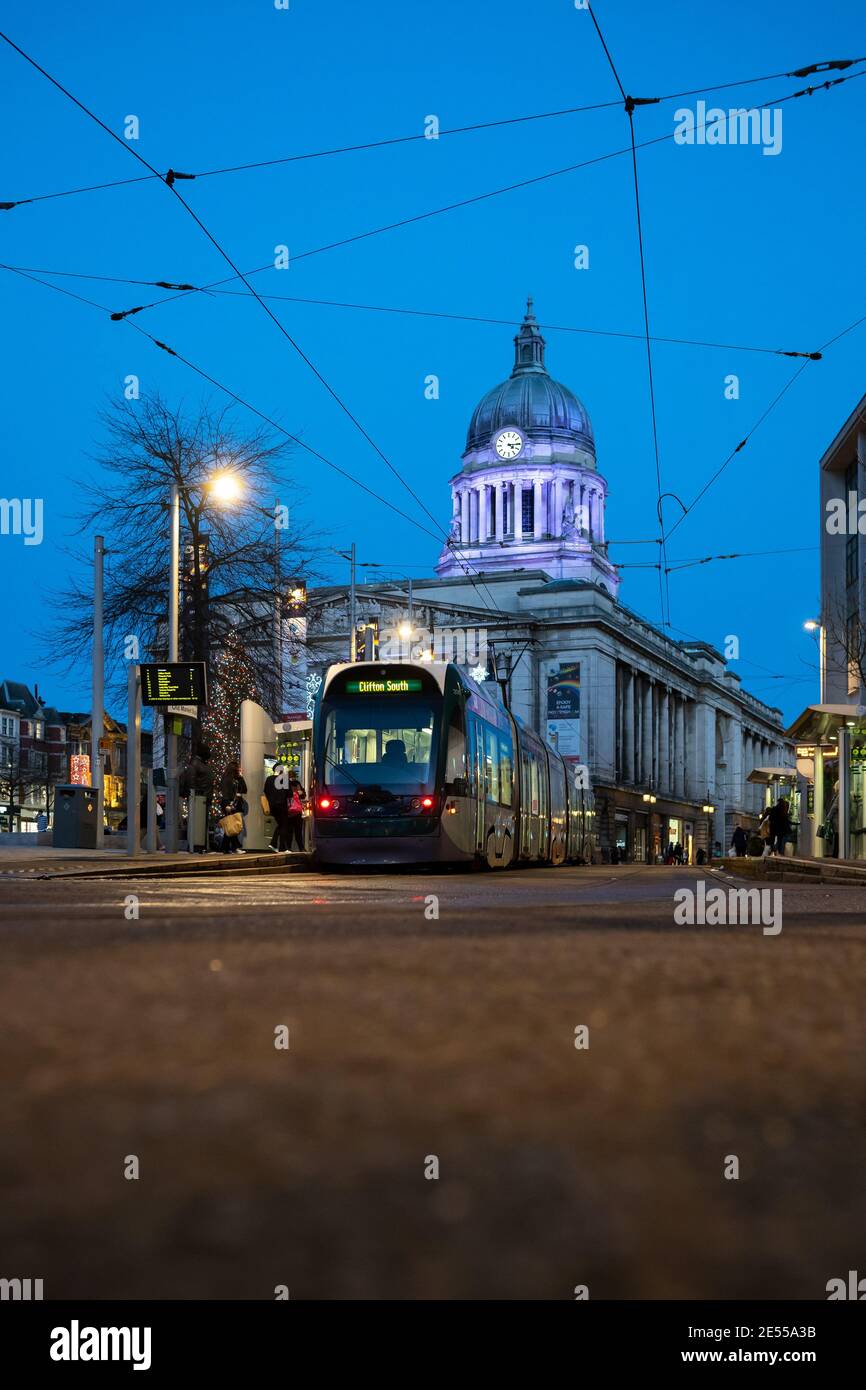 Casa del Consiglio illuminata con tram parcheggiato di fronte illuminato i cavi delle luci di strada notturne vi aspettano i passeggeri che fanno acquisti a bordo Cielo blu Nottingham Foto Stock