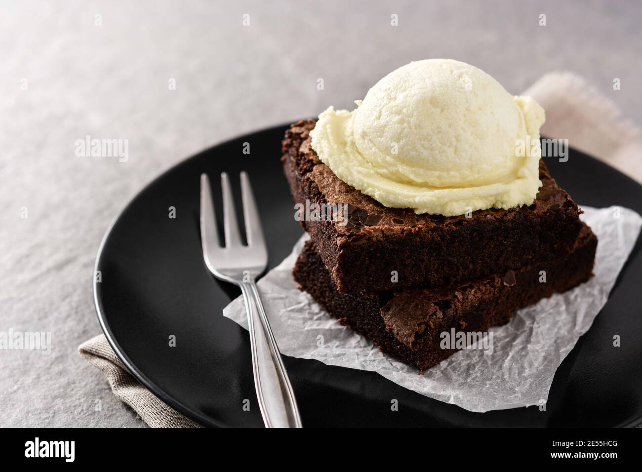 Brownie con cucchiaio di gelato alla vaniglia su pietra grigia Foto Stock