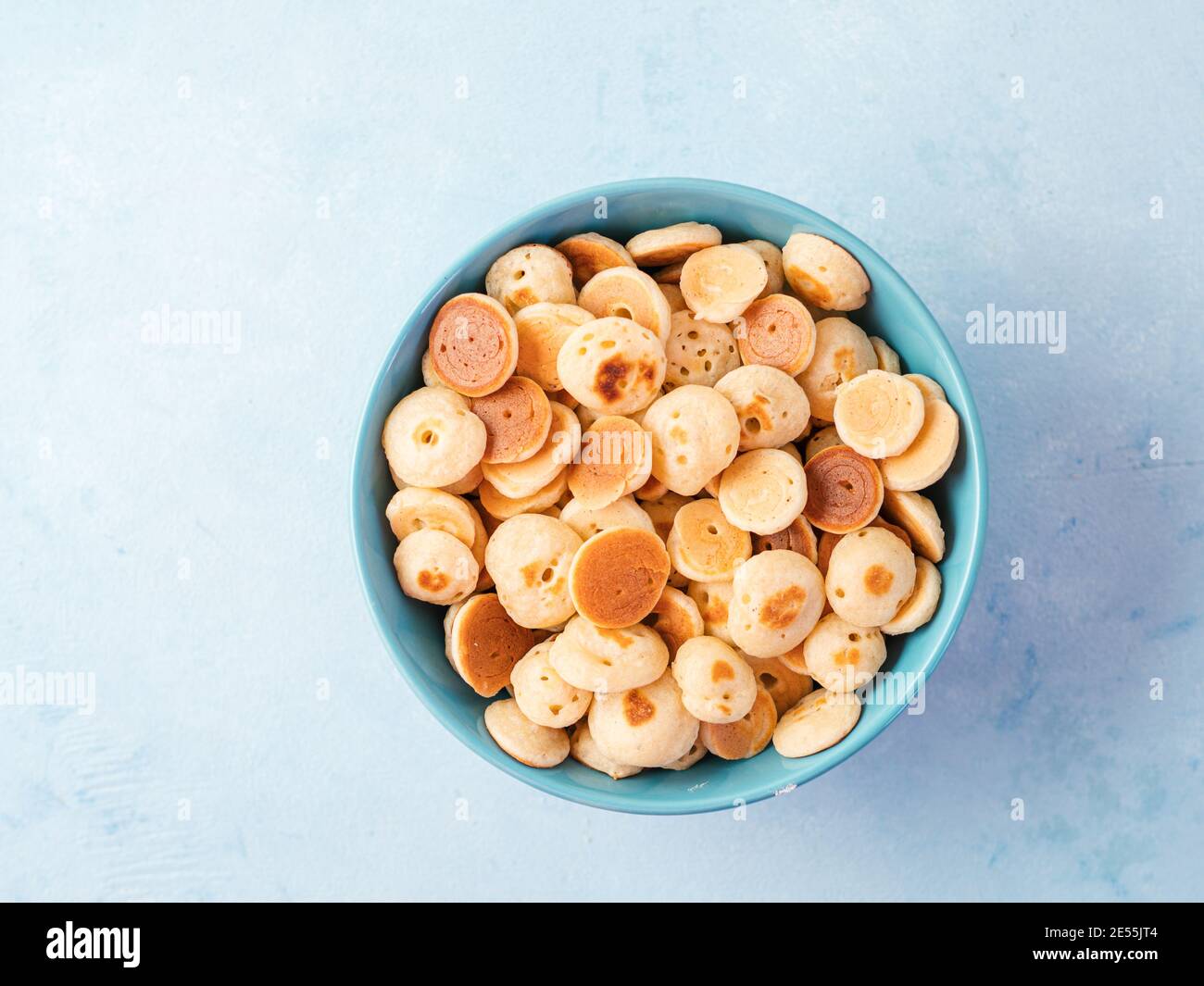 Cibo alla moda - pancake cereali. Un mucchio di mini frittelle di cereali in boul su sfondo blu. Copia spazio a sinistra per il testo. Vista dall'alto o in piano. Foto Stock