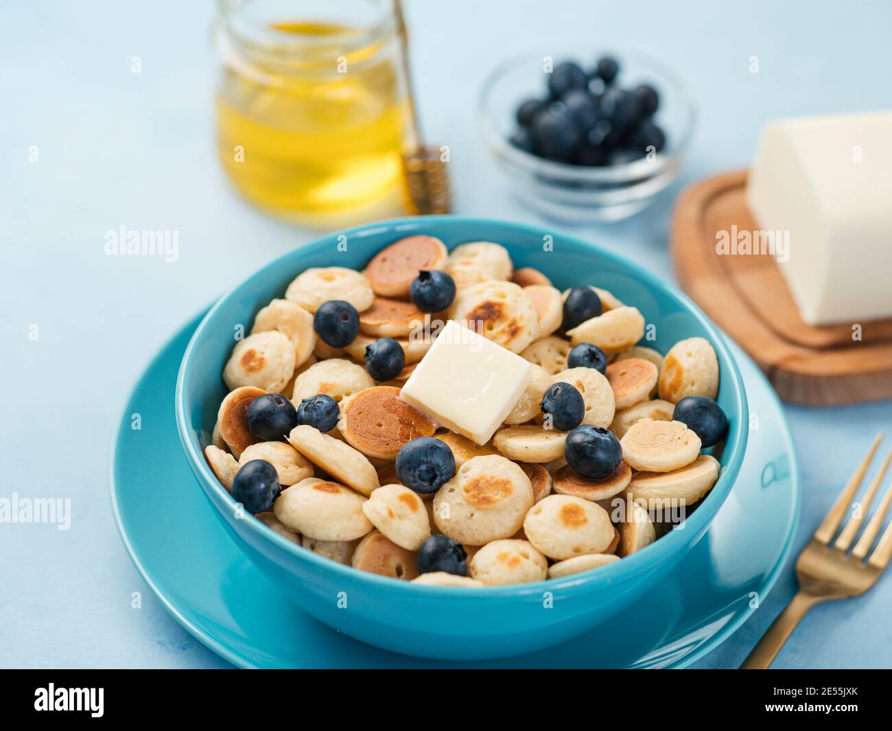 Cibo alla moda - cereali pancake. Un mucchio di mini frittelle di cereali in boul su sfondo blu. Spazio di copia per testo o disegno Foto Stock