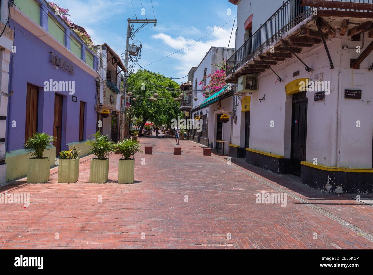 Santa Marta, Colombia -- 22 aprile 2018. I vasi di fiori si bloccano fuori da una strada laterale dal traffico regolare su una colorata strada laterale a Santa Marta, Colombia. Foto Stock