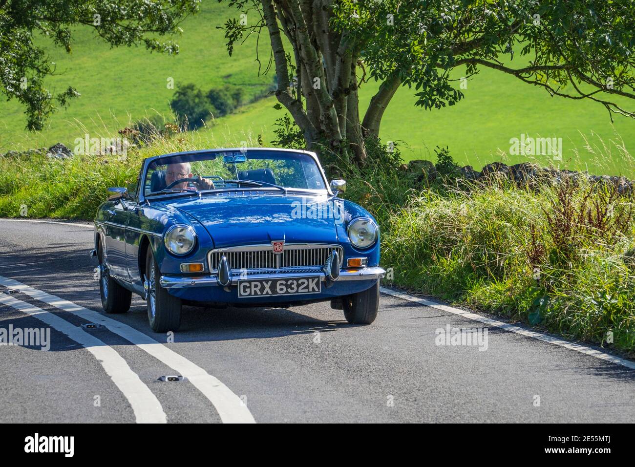 Un roadster MGB entra in una curva a tornanti su una ripida collina. Foto Stock