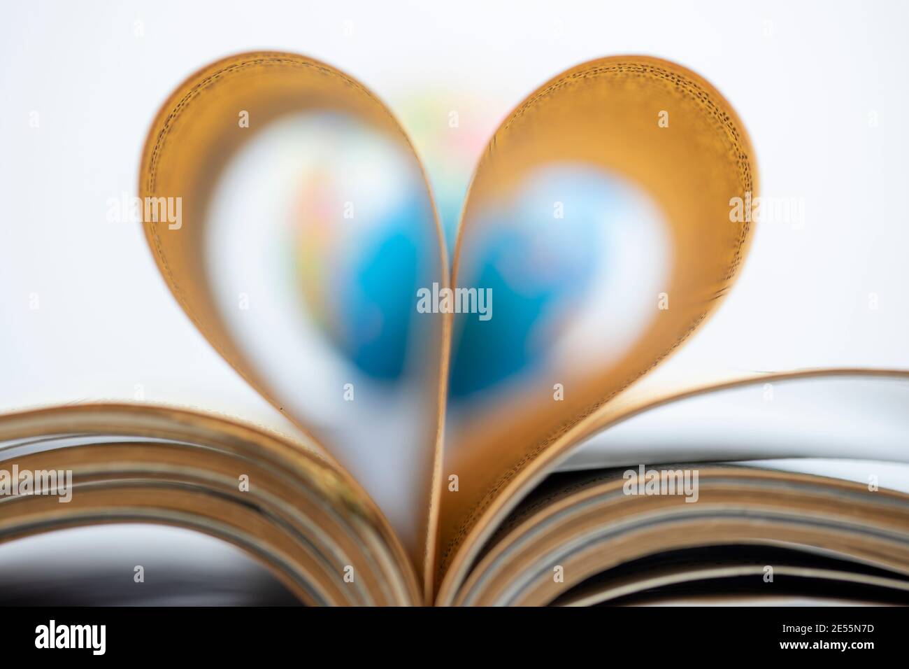 Amore per leggere concept, mondo e pagine di libri ripiegati a forma di cuore Foto Stock