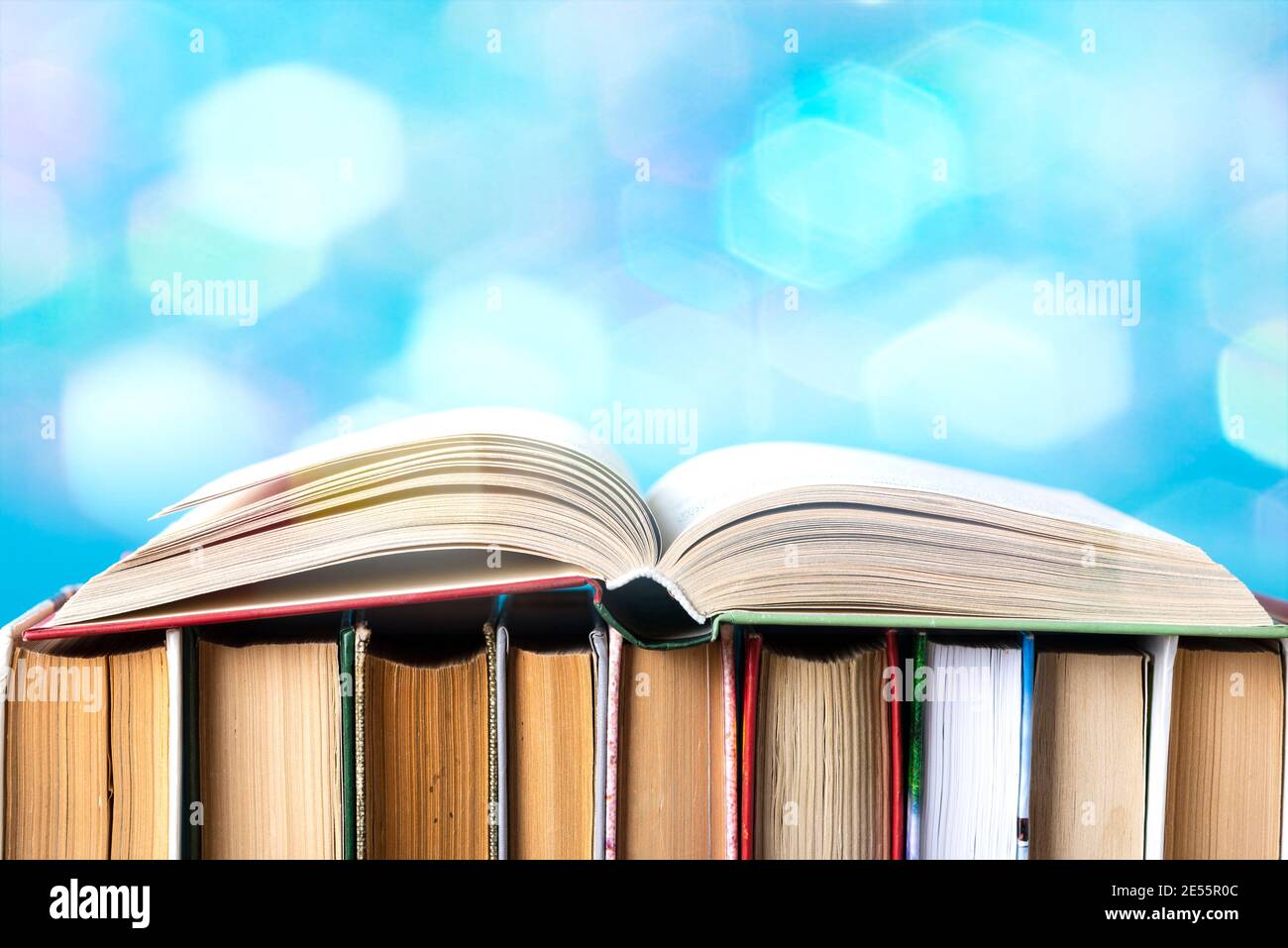 Una composizione semplice di hardback libri, materie libri sul ponte di legno tavolo e sfondo blu. Libri di impilamento senza iscrizioni, vuoto della colonna vertebrale. Torna a sc Foto Stock