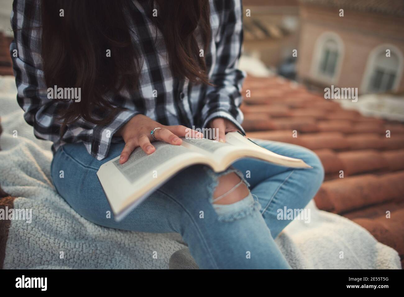 Donna in un momento di relax leggendo sul tetto di casa sua Foto Stock