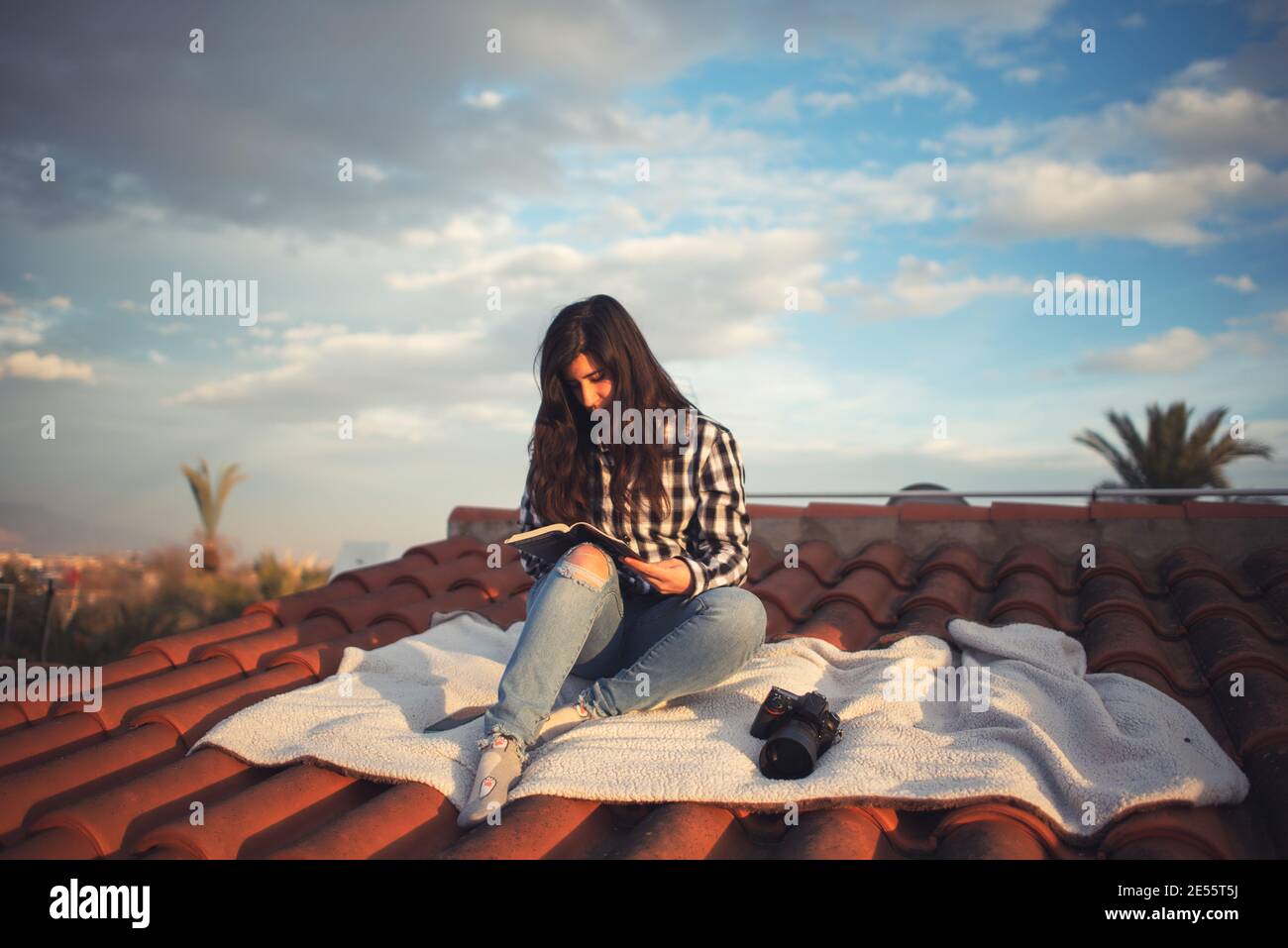 Donna in un momento di relax leggendo sul tetto di casa sua Foto Stock