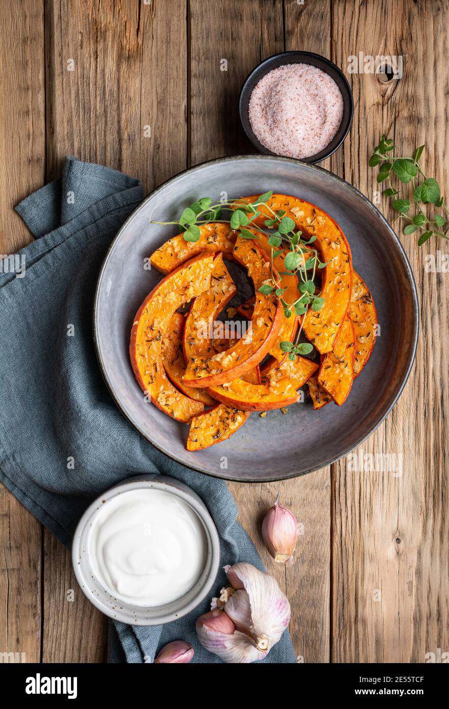 Fettine di zucca di Hokkaido arrostite con olio d'oliva, aglio grattugiato ed erbe, servite con panna acida Foto Stock