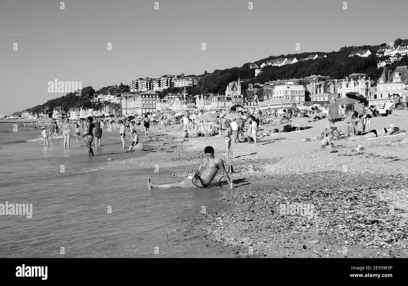 Uomo rilassante con hookah sulla spiaggia. Trouville-sur-Mer, Normandia, Francia. Foto storica in bianco nero. Foto Stock