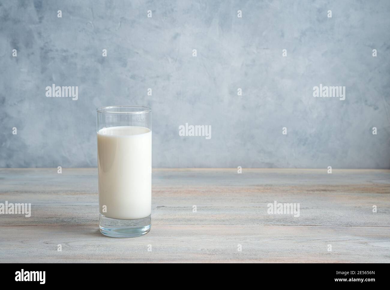 Latte in un lungo bicchiere trasparente su fondo grigio-blu. Vista laterale con spazio per la copia. Foto Stock
