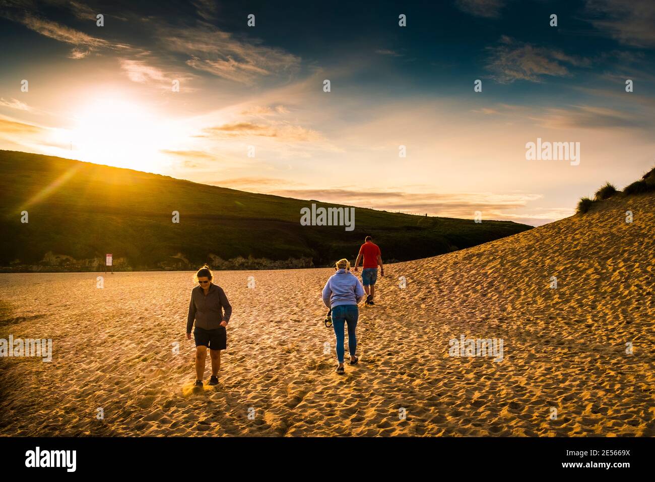 Tarda sera luce del sole mentre la gente cammina attraverso il sistema di dune di sabbia a Holywell Beach in Cornovaglia. Foto Stock