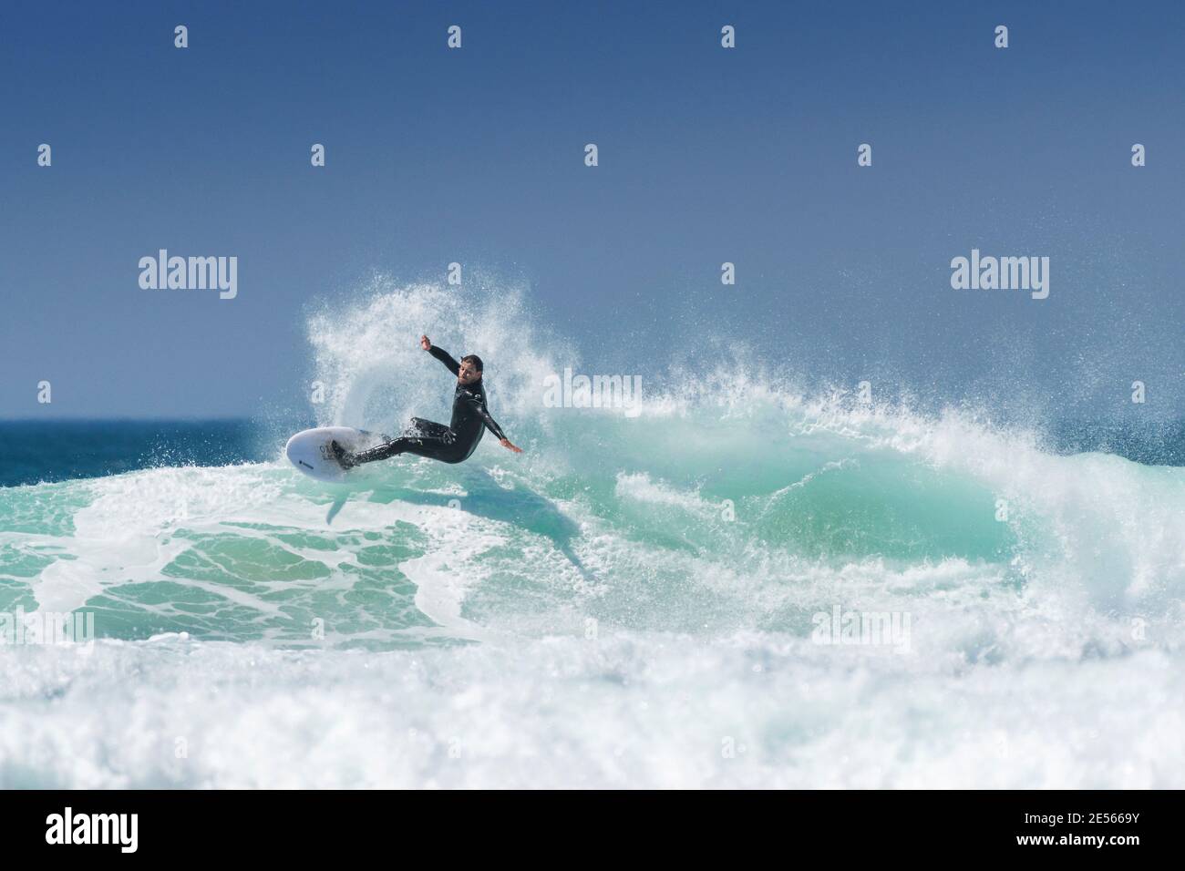 Azione spettacolare come un surfista cavalca un'onda al Fistral a Newquay in Cornovaglia. Foto Stock