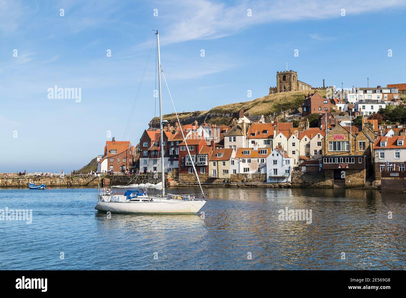 Lo yacht entra nel porto di Whitby sotto un cielo blu. Foto Stock