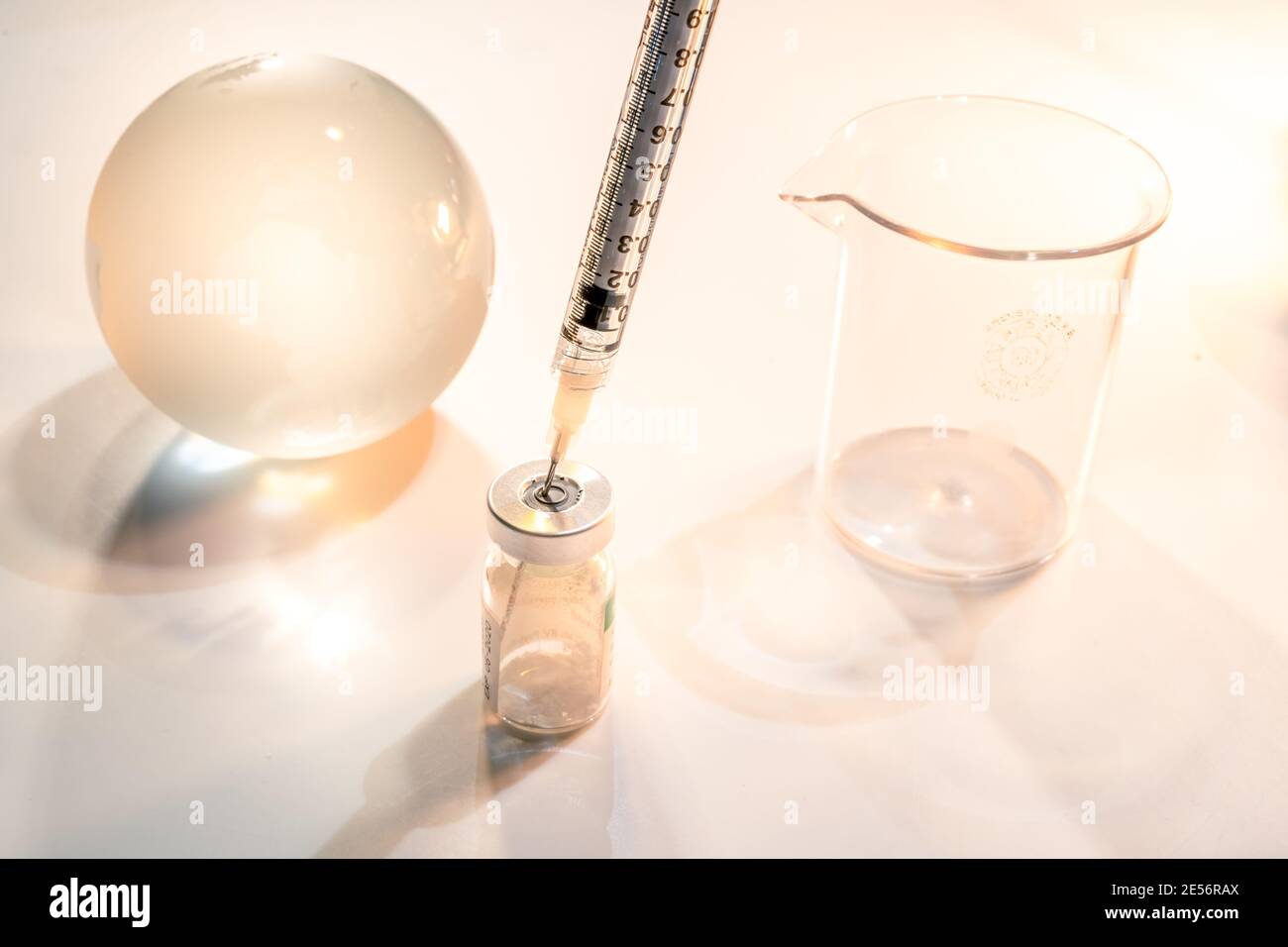 Globo di vetro e siringa con vaccino e becher su sfondo bianco . Concetto globale di assistenza sanitaria Foto Stock