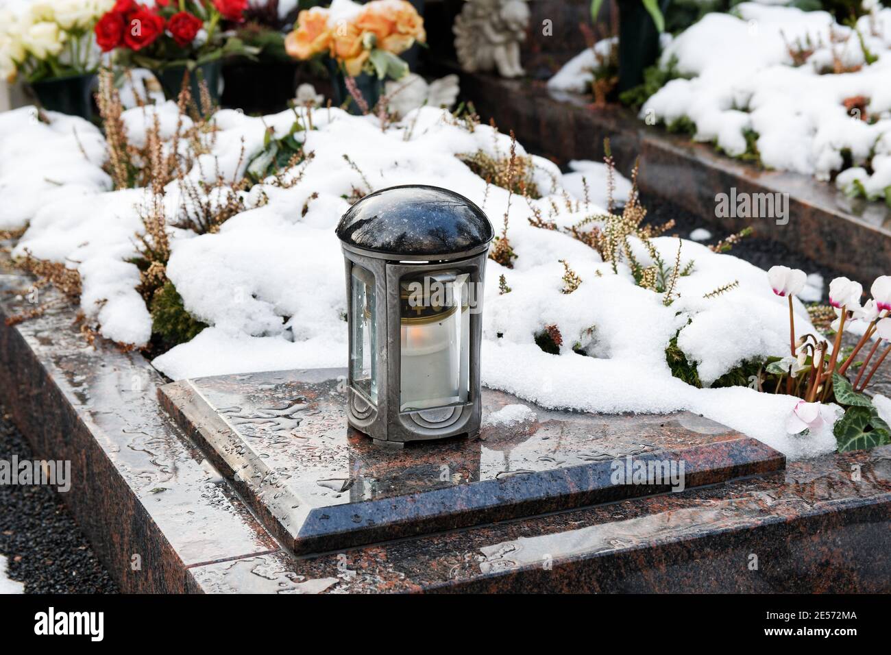 luce grave su una tomba coperta di neve con fiori dentro lo sfondo Foto Stock