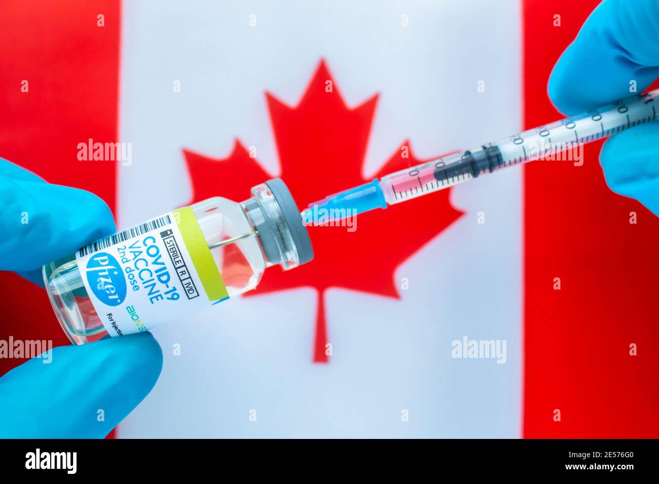 Calgary, Alberta. Canada. 20 gennaio 2021. Un operatore sanitario con un vaccino Pfizer e una siringa con una bandiera canadese sullo sfondo Foto Stock