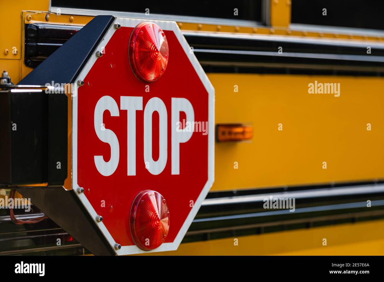 Primo piano del segnale rosso di stop sul bus giallo della scuola. Foto Stock