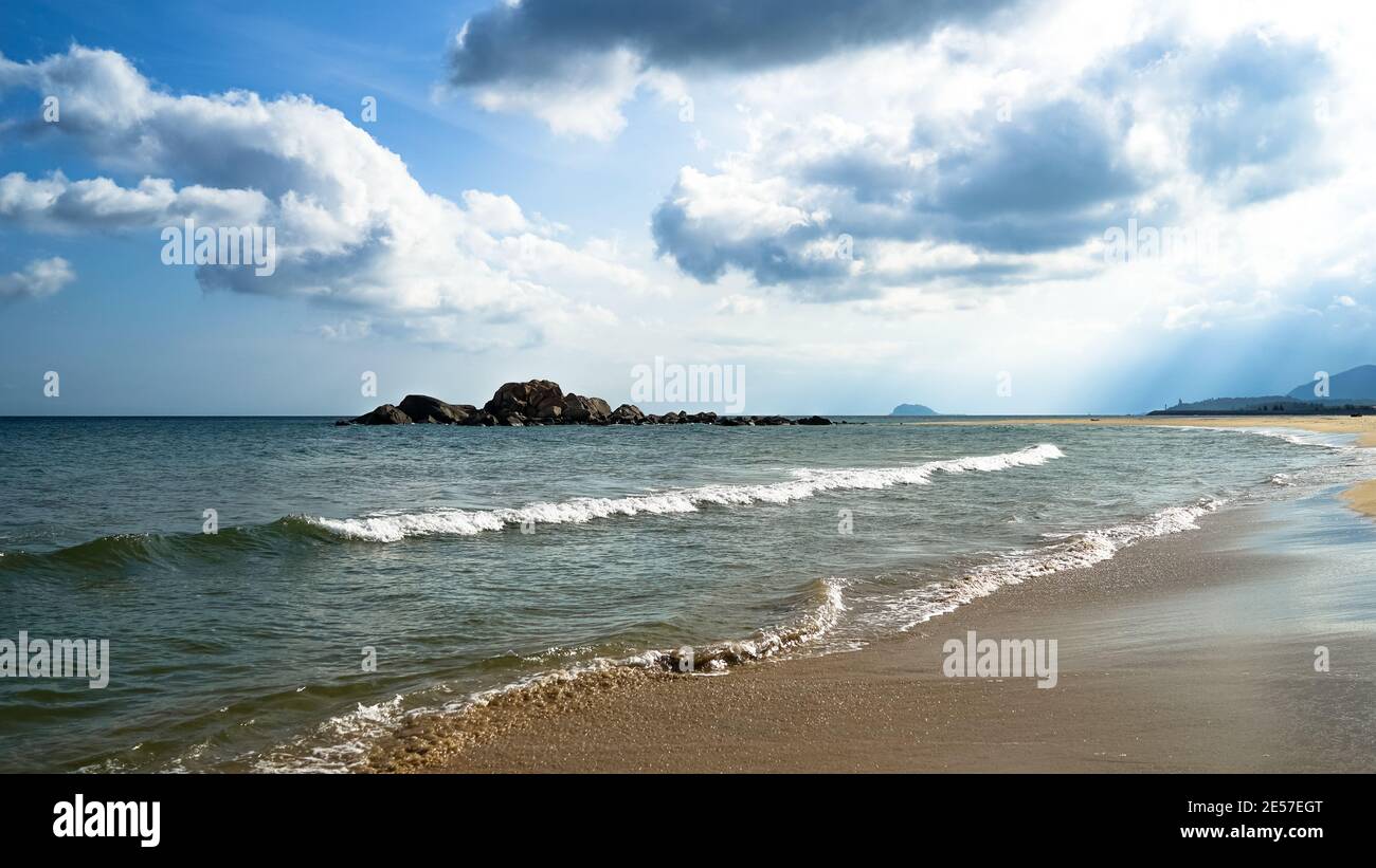 Bella spiaggia con nuvole bianche e sabbia sull'isola di Hainan, tempo soleggiato, vacanza di viaggio estiva, nuvole bianche soffici nel cielo, viaggio in Cina Foto Stock