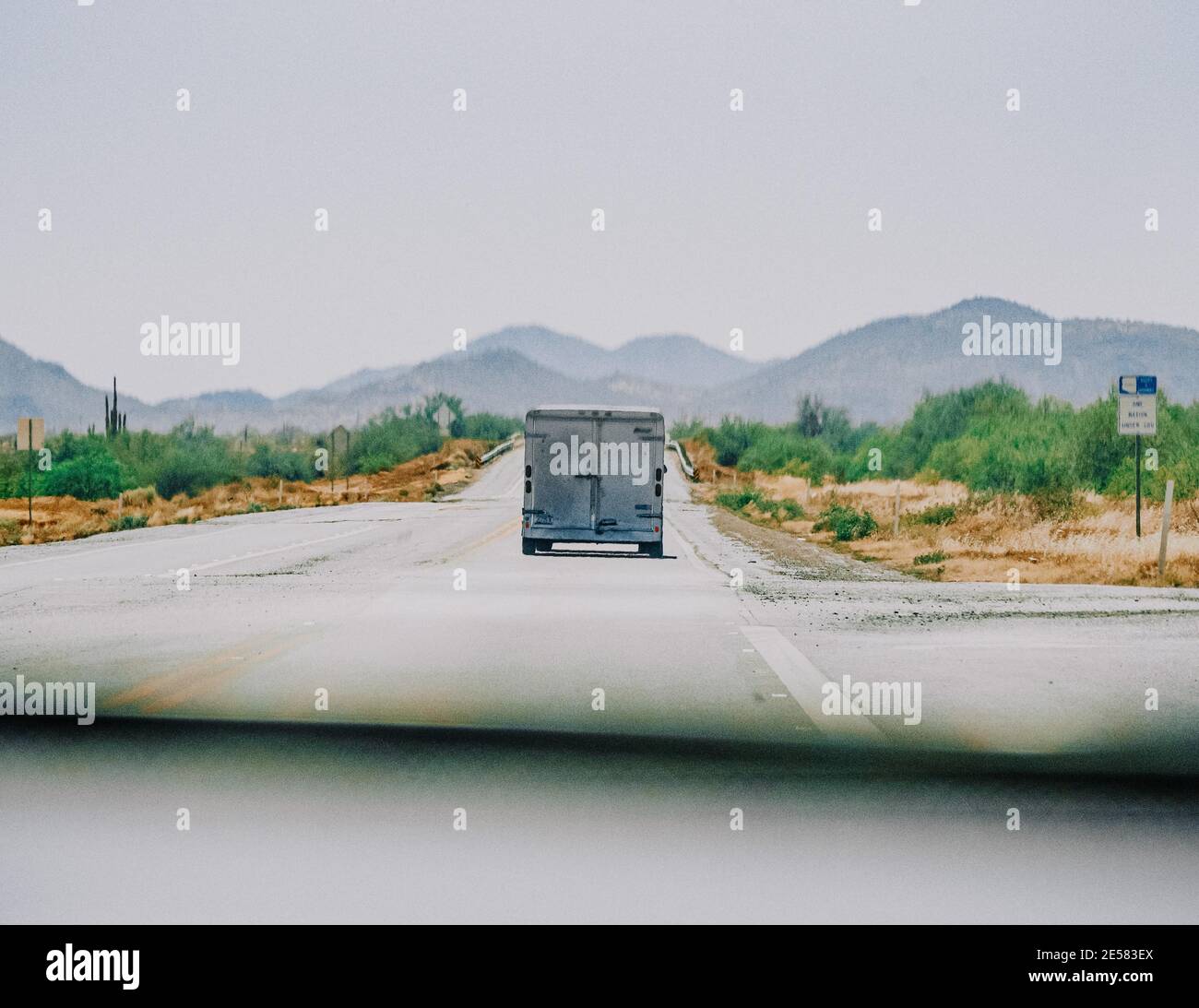 Furgone che viaggia su una strada di campagna con un paesaggio montano sullo sfondo Foto Stock
