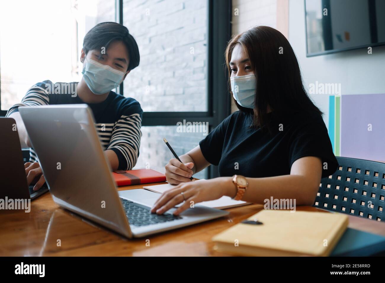 Donne asiatiche e lavoratori di sesso maschile si incontrano con il laptop per le mascherine finanziarie e di protezione dell'usura impediscono il virus della corona o il covid19 nello spazio di lavoro co Foto Stock