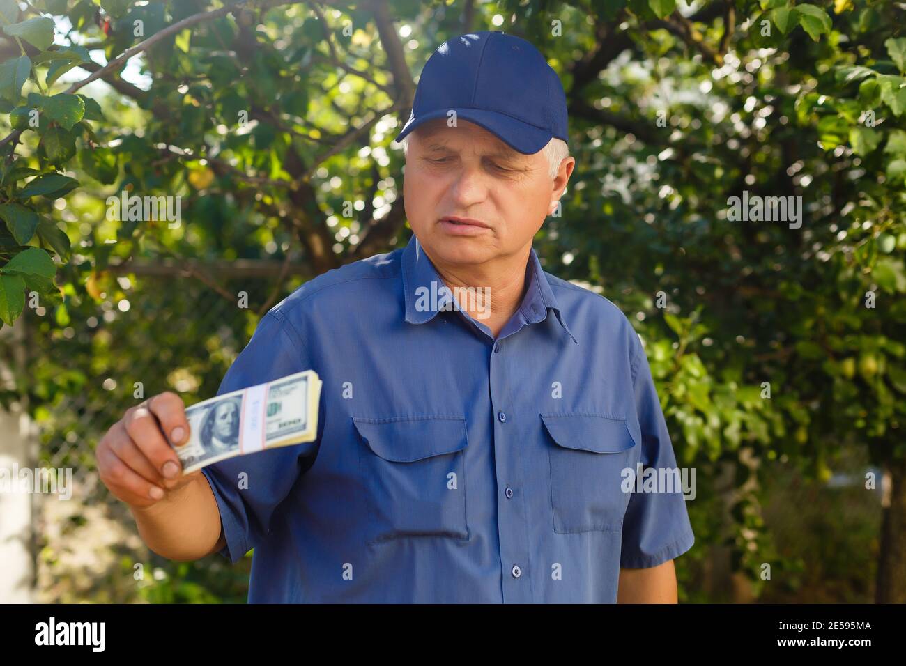 Un uomo anziano che tiene una pila di soldi Foto Stock