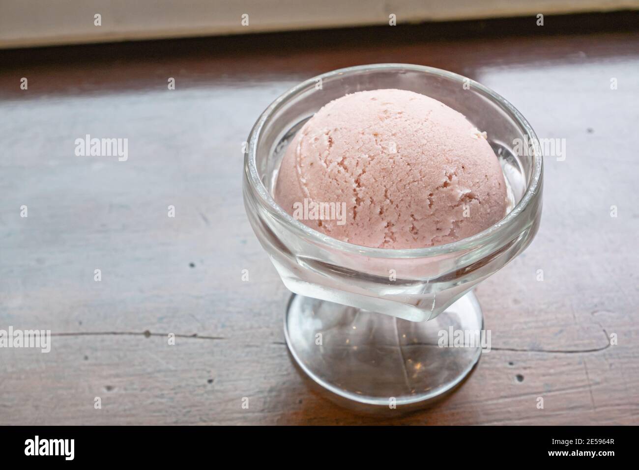 Il primo piano di gustosi scoop fatti in casa gelato alla fragola fresco in tazza di vetro su sfondo tavola di legno vintage. Foto Stock